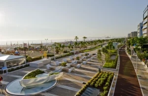 Una moderna passeggiata lungomare con giardini e vista sulla spiaggia.