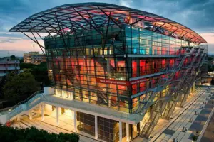 Edificio moderno in vetro illuminato con facciata colorata e struttura a griglia al tramonto