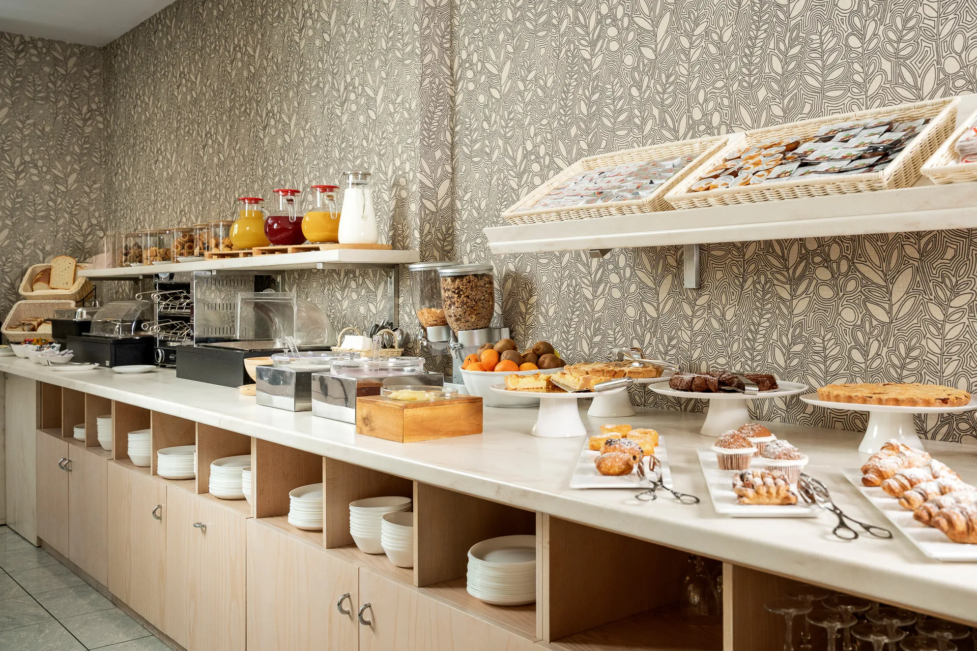 Il buffet della colazione con succhi, torte, cornetti e macchina del caffè