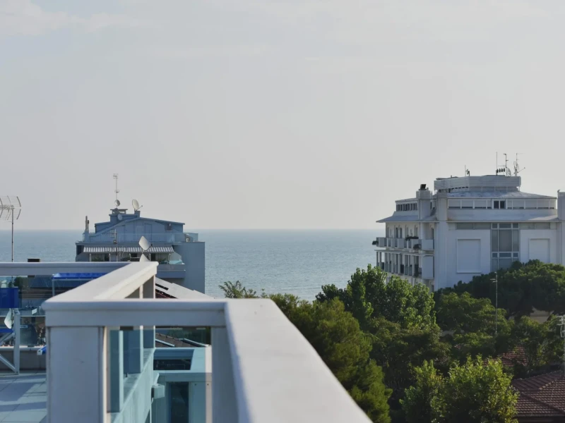 View of the ocean between two buildings with a railing in the foreground.